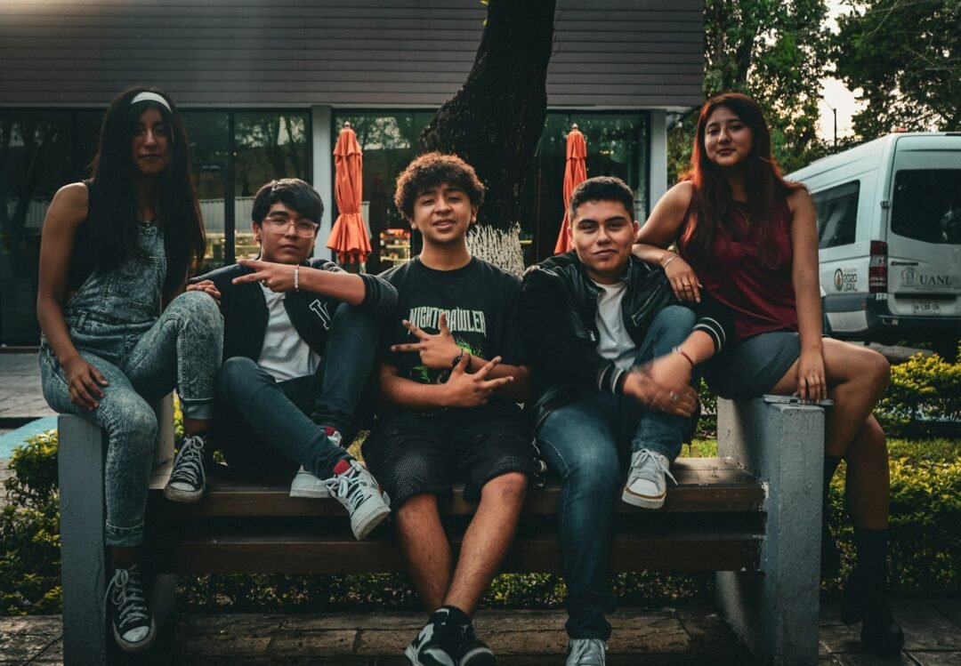 A group of people sitting on top of a wooden bench
